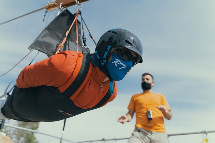 A brave man stands horizontally to jump down the zip line.